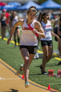 Athlete prepares for pole vault on a track with others watching.