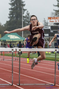 Athlete prepares for pole vault on a track with others watching.