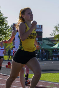 Athlete prepares for pole vault on a track with others watching.
