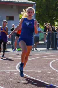 Athlete prepares for pole vault on a track with others watching.