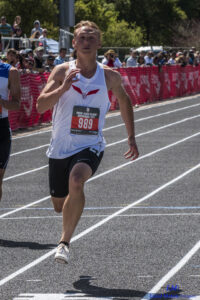 Athlete prepares for pole vault on a track with others watching.