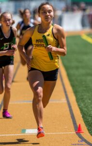 Athlete prepares for pole vault on a track with others watching.