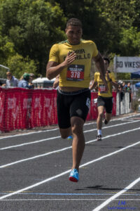 Athlete prepares for pole vault on a track with others watching.