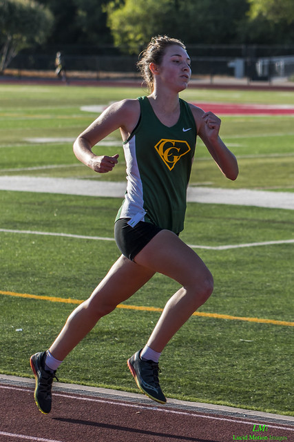 Athlete prepares for pole vault on a track with others watching.
