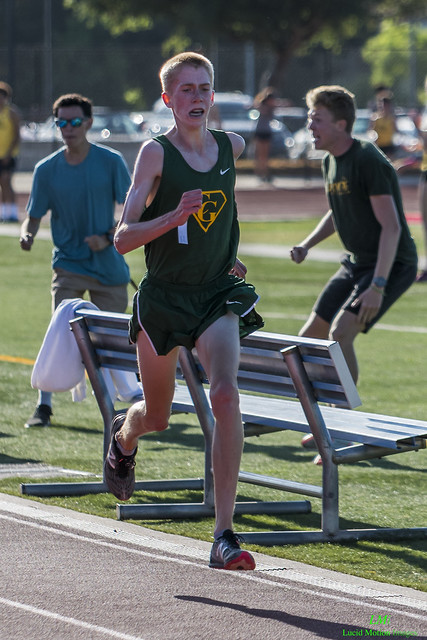 Athlete prepares for pole vault on a track with others watching.