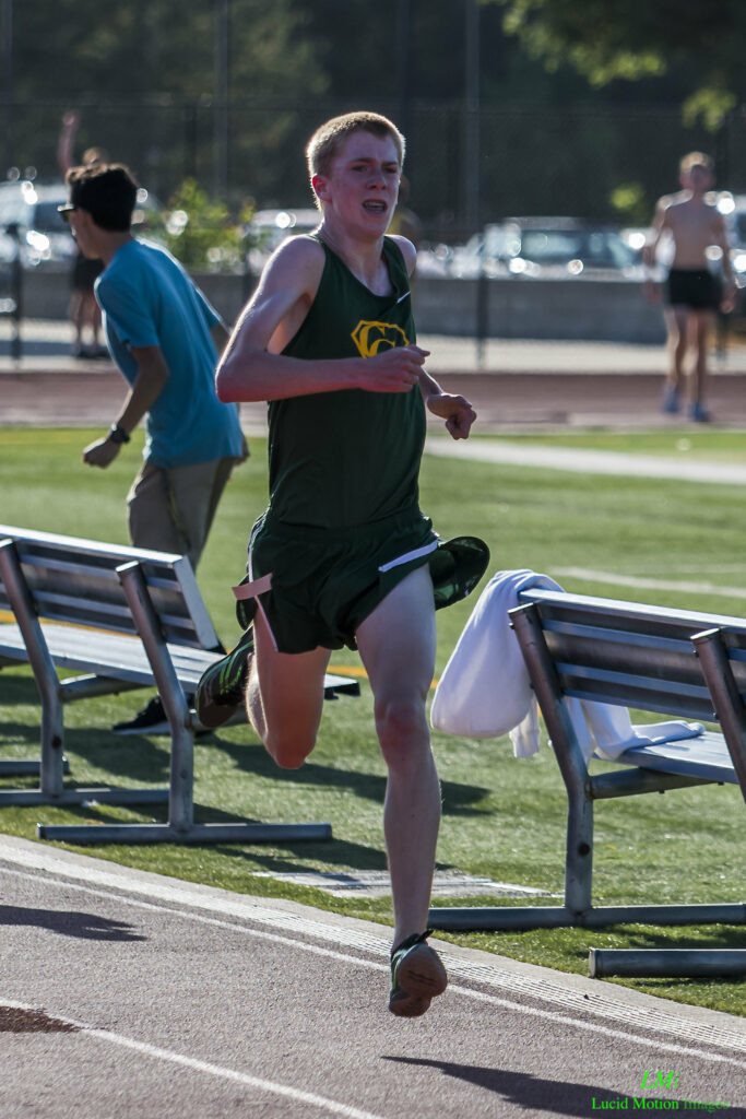 Athlete prepares for pole vault on a track with others watching.