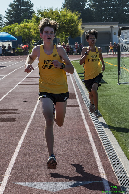 Athlete prepares for pole vault on a track with others watching.