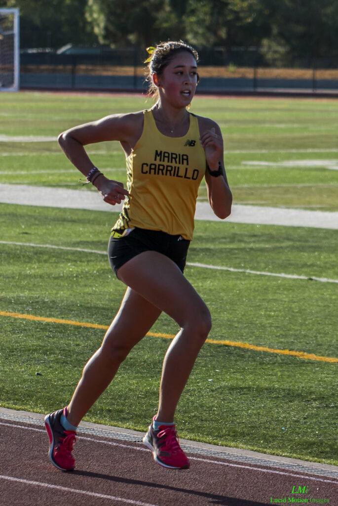 Athlete prepares for pole vault on a track with others watching.