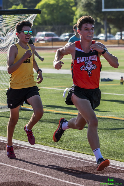 Athlete prepares for pole vault on a track with others watching.