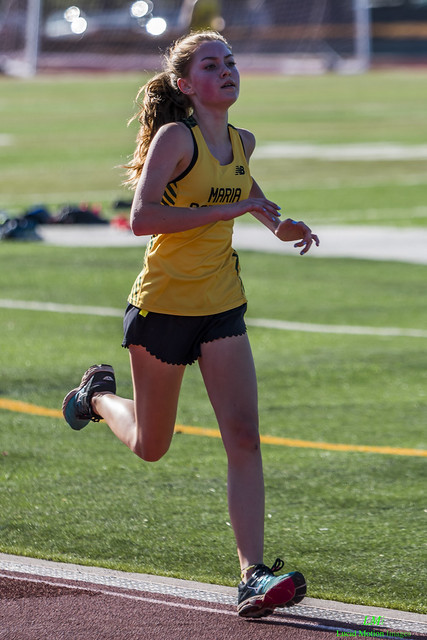 Athlete prepares for pole vault on a track with others watching.