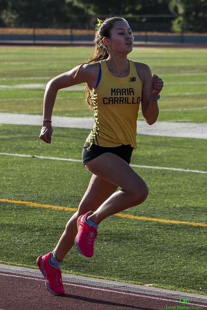 Athlete prepares for pole vault on a track with others watching.