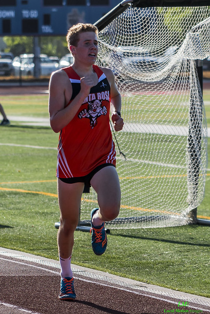 Athlete prepares for pole vault on a track with others watching.
