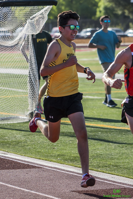 Athlete prepares for pole vault on a track with others watching.
