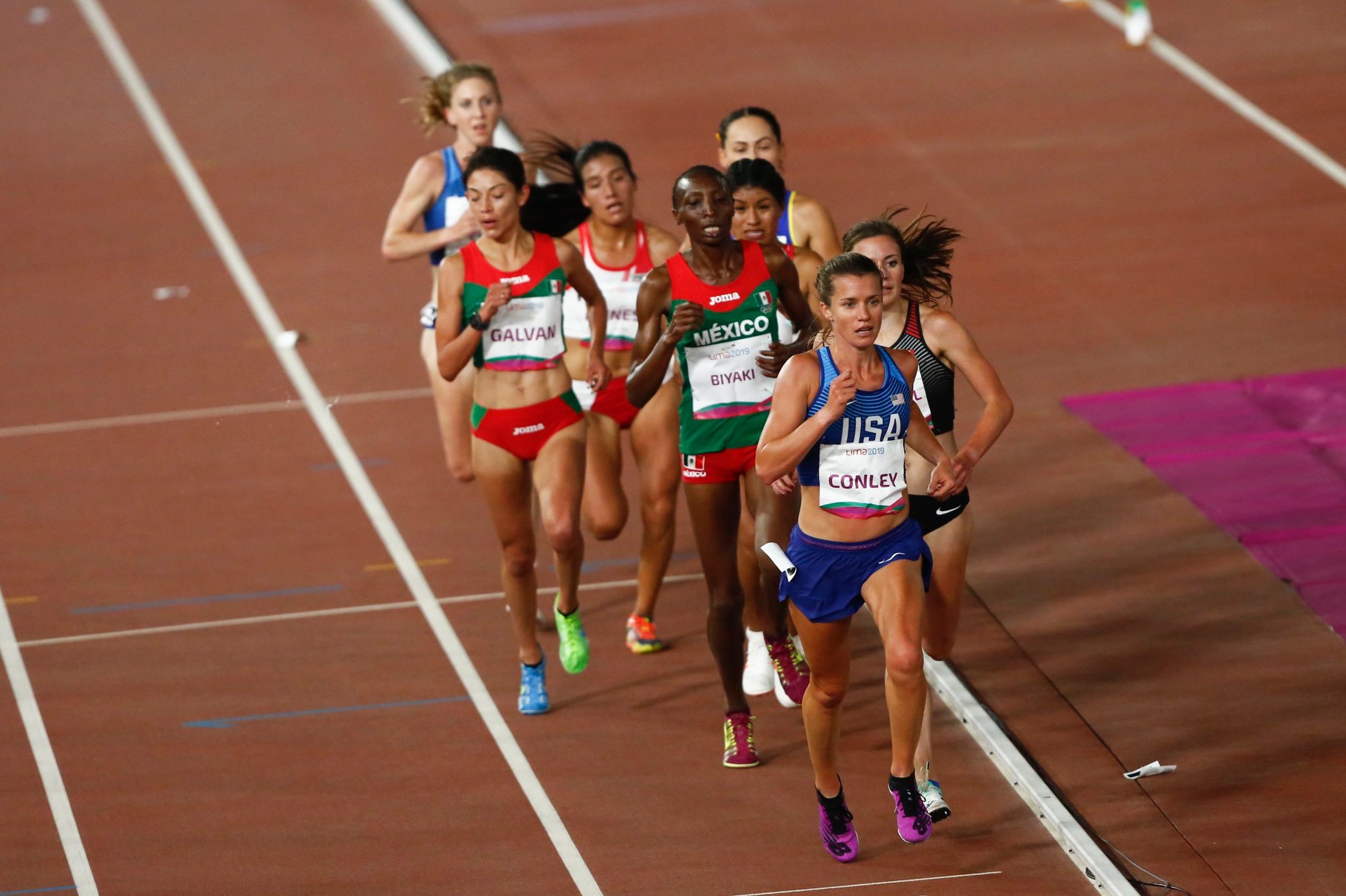 Athlete prepares for pole vault on a track with others watching.