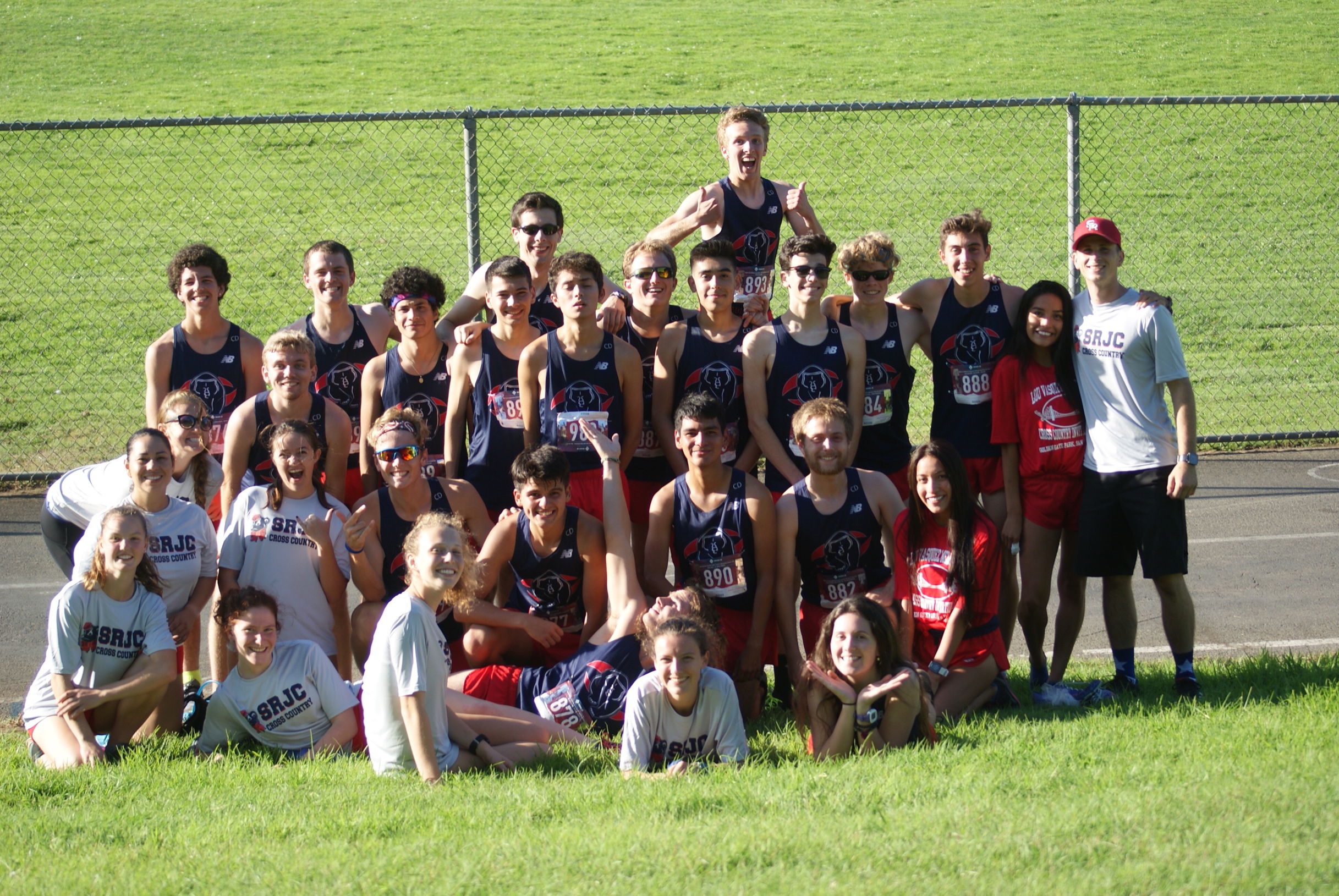 Athlete prepares for pole vault on a track with others watching.