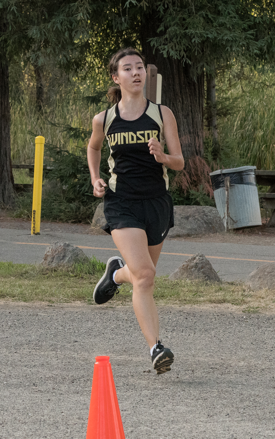 Athlete prepares for pole vault on a track with others watching.