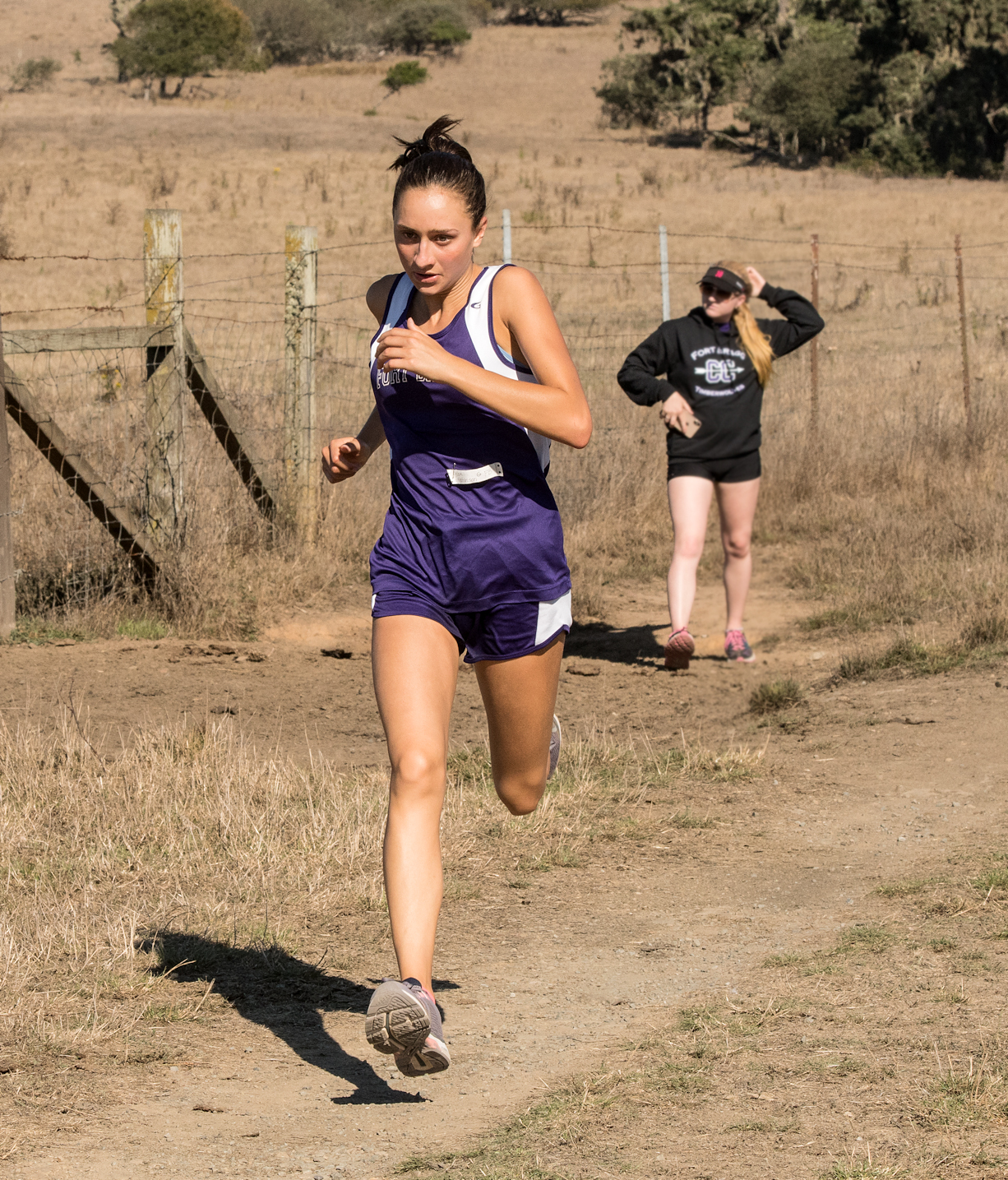 Athlete prepares for pole vault on a track with others watching.