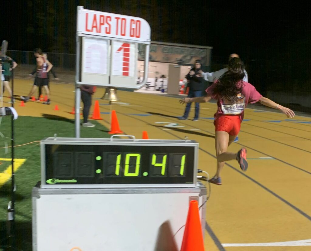 Athlete prepares for pole vault on a track with others watching.