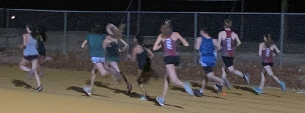Athlete prepares for pole vault on a track with others watching.