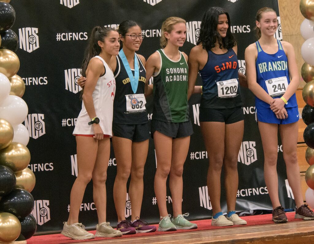 Athlete prepares for pole vault on a track with others watching.