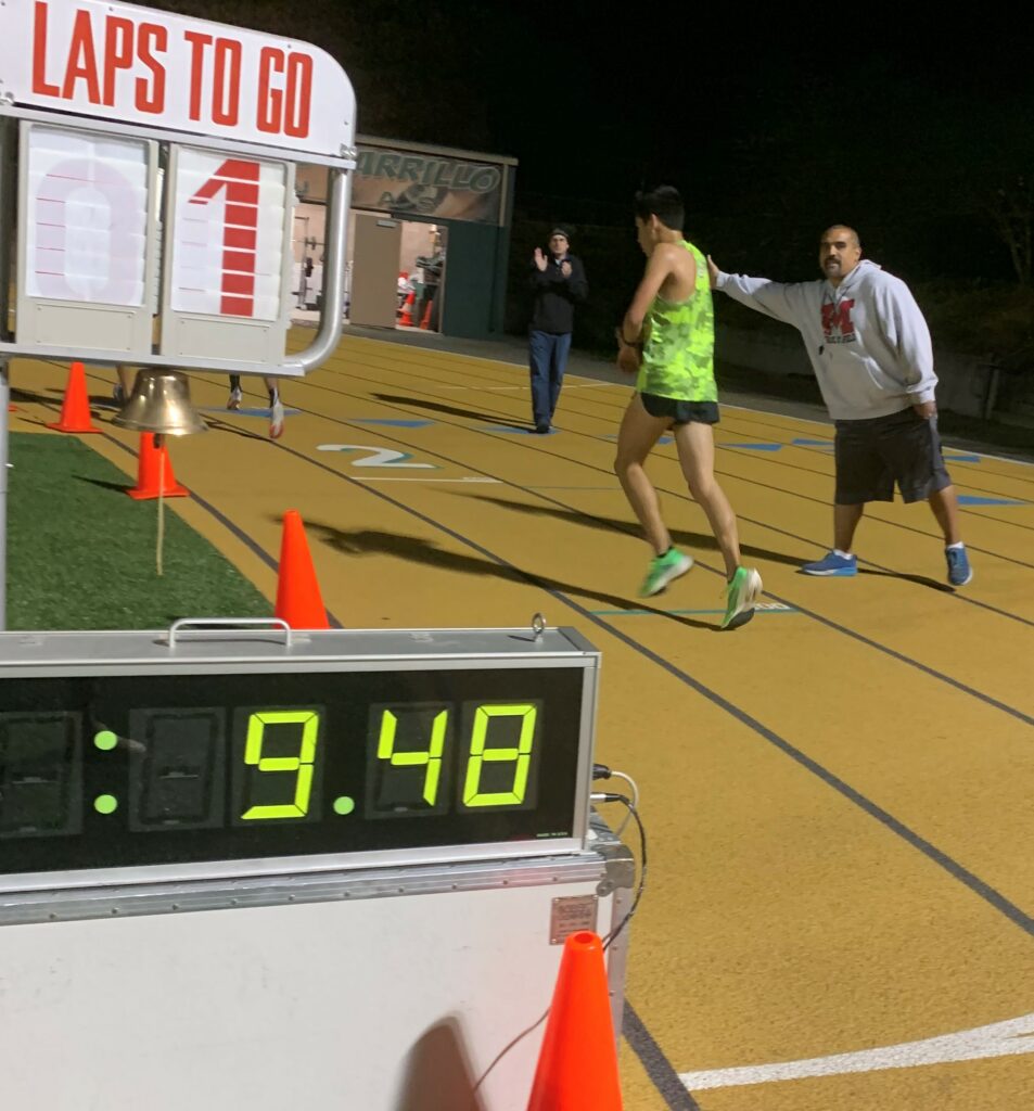 Athlete prepares for pole vault on a track with others watching.