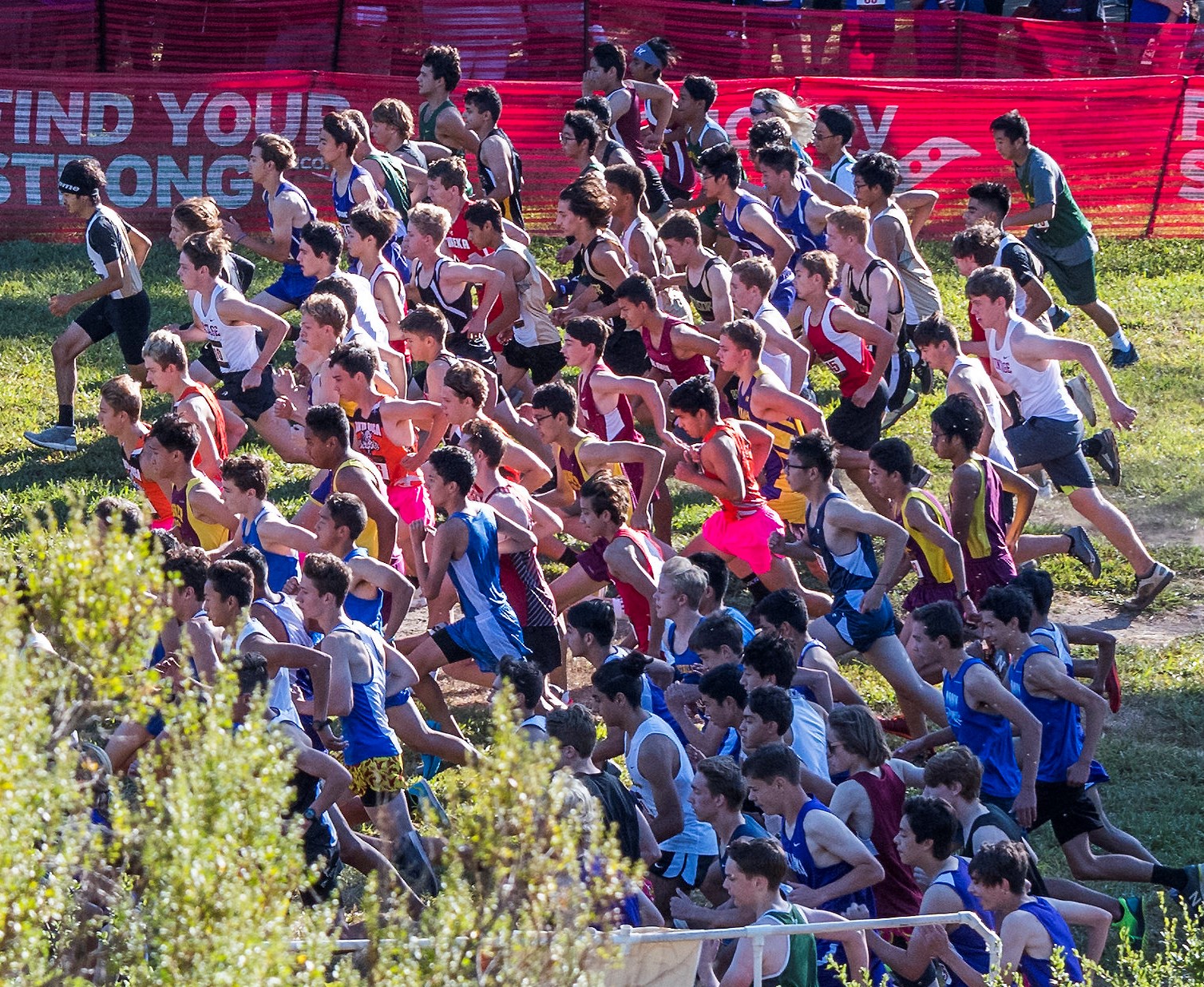 Athlete prepares for pole vault on a track with others watching.