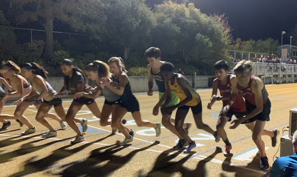 Athlete prepares for pole vault on a track with others watching.