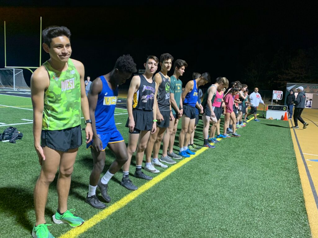 Athlete prepares for pole vault on a track with others watching.