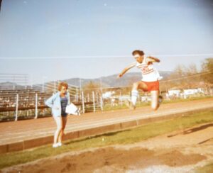 Athlete prepares for pole vault on a track with others watching.